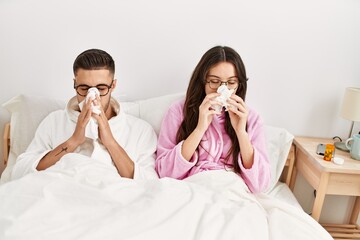 Sticker - Young hispanic couple sick lying in bed at home.