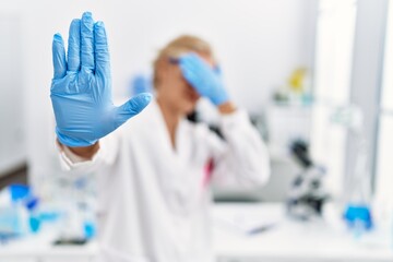 Sticker - Middle age blonde woman working at scientist laboratory covering eyes with hands and doing stop gesture with sad and fear expression. embarrassed and negative concept.