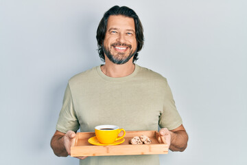 Poster - Middle age caucasian man holding breakfast tray with cookies and coffee smiling with a happy and cool smile on face. showing teeth.