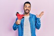 © Krakenimages.com - Handsome hispanic man with beard holding packing tape celebrating achievement with happy smile and winner expression with raised hand