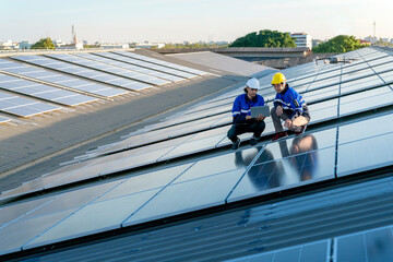 Specialist technician professional engineer with laptop and tablet maintenance checking installing solar roof panel on the factory rooftop under sunlight. Engineers team survey check solar panel roof.