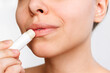 © Марина Демешко - Cropped shot of a young caucasian woman applying a hygienic lipstick on her lips isolated on a white background. Moisturizing chapstick for dry lips. Close up