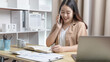 © Puwasit Inyavileart - Asian female worker talking on phone and working on laptop with smiling face, Office staff work and telephone conversations, Take notes for reminders, Business conversation over the phone.
