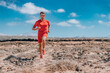 © Maridav - Runner ultra running man athlete wearing smartwatch, sunglasses, red compression clothes for trail run. Athlete training endurance race doing triathlon workout in desert