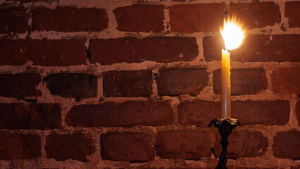 Wall Mural - Candle flame close-up on a red wall background. Melted Wax Candle light border design. Long Exposure. Darkness.