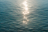 Fototapeta Las - Detail of a sunlight reflecting in glittering sea. sparkler in water - background. sea water with sun glare and ripple. Powerful and peaceful nature concept