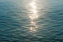 Detail Of A Sunlight Reflecting In Glittering Sea. Sparkler In Water - Background. Sea Water With Sun Glare And Ripple. Powerful And Peaceful Nature Concept