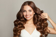 © artmim - Portrait of beautiful woman touching her long healthy curly hair and looking at camera on gray background