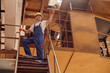 Cheerful worker standing on stairs in engineering plant shop