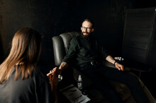 A Satisfied Man With A Beard Sits In A Leather Chair And Is Given A Man's Manicure. The Concept Of Male Manicure.