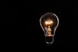 © taveesaksri - tungsten light bulb lit on black background