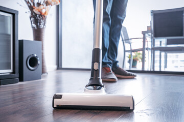 Man cleaning the house with a portable vacuum cleaner