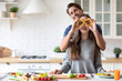 © BestForYou - Positive young couple in love having fun while cooking in kitchen at home, making eyeglasses from bell pepper slices. Enjoying healthy preparing food