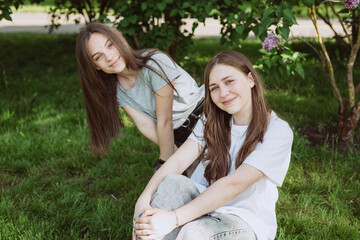 Wall Mural - Two young happy teen girls having fun in the park on a summer day. Female friendship. Soft selective focus.