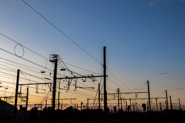  Silhouettes at sunset of electrical train equipment, wires, cables, lines and poles, Leuven, Belgium