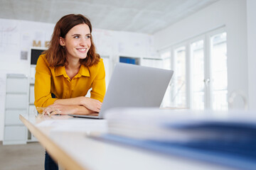 Young businesswoman smiling to herself in happy anticipation