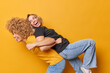 Happy optimistic women foolish around give each other piggyback ride laugh and have fun dressed in casual t shirts and jeans isolated over yellow background. Friendship relationship concept.