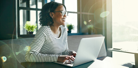 Smiling young African woman working online with her laptop