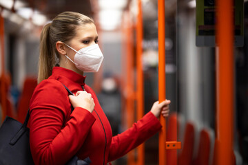 Facial mask concept. A woman wears a mandatory mask inside public transport areas such as a train station, bus and metro. European woman traveler.