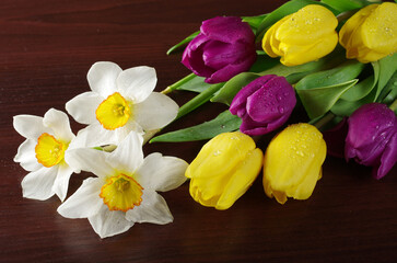 Wall Mural - Bouquet of fresh daffodils and tulips on a wooden table.