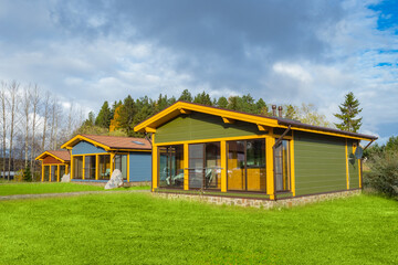 Wall Mural - Cottage village on the background of a beautiful sky. One-story houses on lawns. Autumn in the cottage village. Private houses with terraces. Panoramic Windows of buildings.