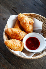 Wall Mural - French croissant with jam in wicker basket on wooden table.