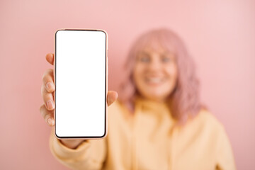 happy young woman showing empty cellphone screen on pink studio background.