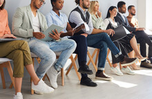 Crop Image Of Diverse Employees Sit On Chairs In Row Listen To Seminar Or Training In Office. Job Candidates Or Applicants In Line Wait For Interview For Vacant Position. Employment, Hiring Concept.