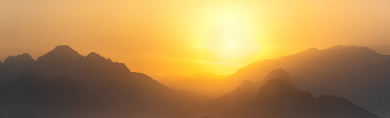 Wall Mural - orange panorama - misty mountains at sunset