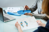 Fototapeta Przestrzenne - Doctor consulting patient on custom orthotic insoles in a clinic for a personalised custom fit.