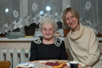 Poster - An old woman at the table with her adult daughter.