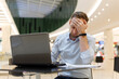 © vladdeep - Feeling tired. Frustrated young man covering his face with hands while working on laptop