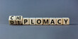 Diplomacy or chiplomacy symbol. Turned wooden cubes and changed the concept word diplomacy to chiplomacy. Beautiful grey table, grey background, copy space. Business, diplomacy or chiplomacy concept.