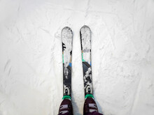 Top Above View Of Female Womens Legs In Skis On White Icy Snow Surface, Mountain Track Background, Skier Legs On Downhill Start Straight Line Rows Ski Slope Piste. Winter Active Sport Outdoor Concept