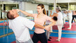 © JackF - Basic self-defense techniques for women. Girl blocking hand of male opponent and launching strike in chin with fist during workout at gym