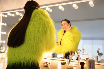 Sticker - Young woman applying make up near illuminated mirror indoors