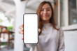 © Farknot Architect - Mockup image of a young woman holding and showing a mobile phone with blank white screen