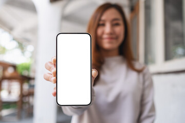 Poster - Mockup image of a young woman holding and showing a mobile phone with blank white screen