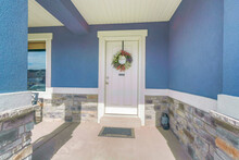 Porch Of A Blue House With White Front Door With Wreath