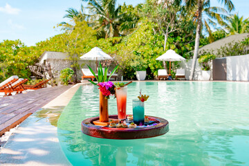 Wall Mural - served floating tray in swimming pool with drinks and snacks on tropical island resort in Maldives, cocktails and canapes for romantic date or honeymoon in luxury hotel, travel concept