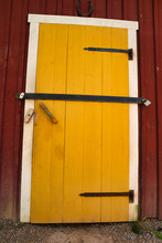 A Yellow Door On A Red Wooden House In Sweden, Locked With Two Large Locks.