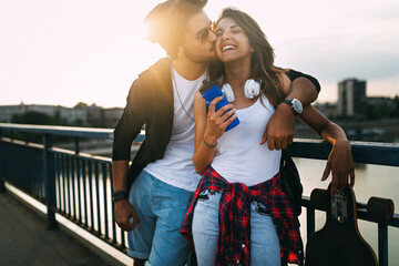 Wall Mural - Portrait of happy couple having fun while driving a long board in city. People skateboard concept