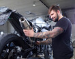 © Westend61 - Tattooed mechanic examining exhaust pipe of motorcycle in workshop