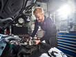 © Westend61 - Smiling young blond mechanic repairing car engine in auto shop