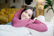 © Westend61 - Happy young woman leaning on sofa in living room