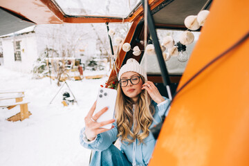 Wall Mural - Young caucasian woman taking selfie photo, sitting in a car while traveling in road trip.