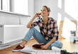 © Syda Productions - repair, people and real estate concept - happy smiling woman with blueprint and pencil sitting on floor at home and calling on smartphone
