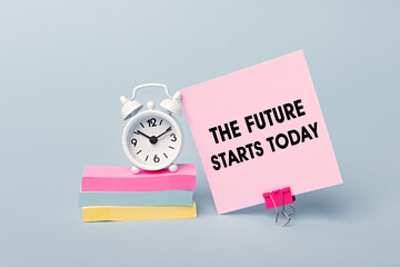 The future starts today - concept of text on pink sticky note. Closeup of a personal agenda. Alarm clock and colorful stickers light blue background