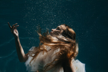 Portrait of beautiful woman in bridal dress underwater.