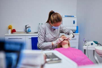 Wall Mural - Female dentist examining the teeth of a young woman